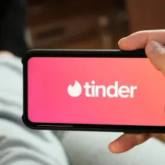 Dłoń trzyma smartfon z otwartą aplikacją Tinder.