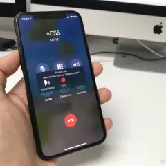 Dłoń trzyma iPhone'a z ekranem rozmowy. Widoczna opcja nagrywanie rozmów z przyciskiem "Start".