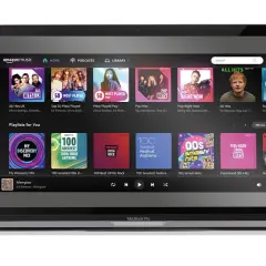 Laptop z interfejsem Amazon Music Unlimited. Widoczne playlisty: "All Hits UK", "Pop Right Now", "My Discovery Mix" i "Feel-Good 00s Hits".