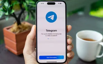 Dłoń trzyma smartfon z otwartą aplikacją Telegram. Komunikator ten jest szybki, darmowy i bezpieczny.