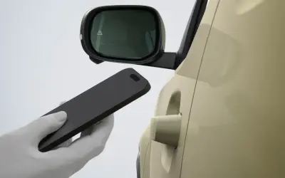 Dłoń w białej rękawiczce zbliża smartfon do klamki samochodu Hyundai. Bluelink umożliwia bezkluczykowe otwieranie.