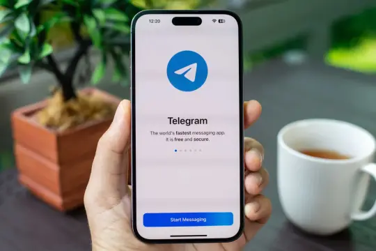 Dłoń trzyma smartfon z otwartą aplikacją Telegram. Komunikator ten jest szybki, darmowy i bezpieczny.