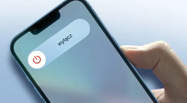 Dłoń trzyma iPhone'a z widocznym suwakiem "wyłącz" i ikoną zasilania.