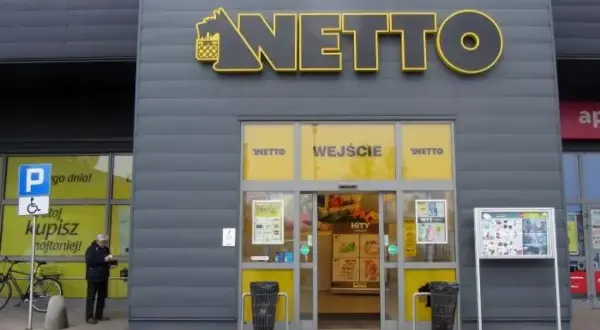 Wejście do sklepu Netto. Obok parking dla niepełnosprawnych. Aplikacja Netto pomoże Ci znaleźć najlepsze okazje.