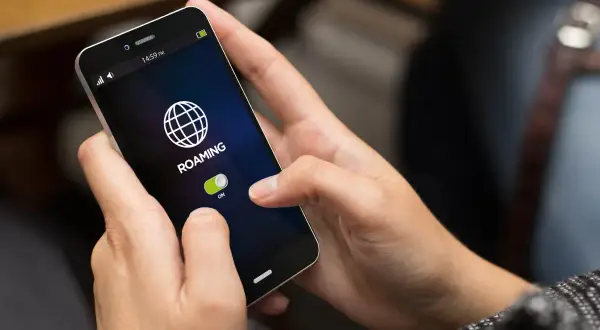 Dłoń włącza roaming na telefonie, przygotowując się do podróży.