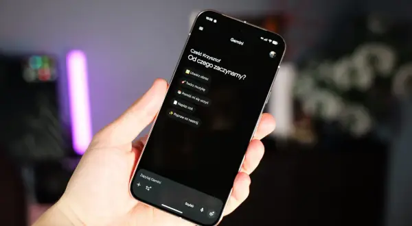 Dłoń trzyma telefon z interfejsem Gemini, oferującym opcje tworzenia obrazów, muzyki i nauki.
