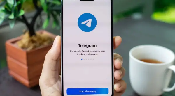 Dłoń trzyma smartfon z otwartą aplikacją Telegram. Komunikator ten jest szybki, darmowy i bezpieczny.