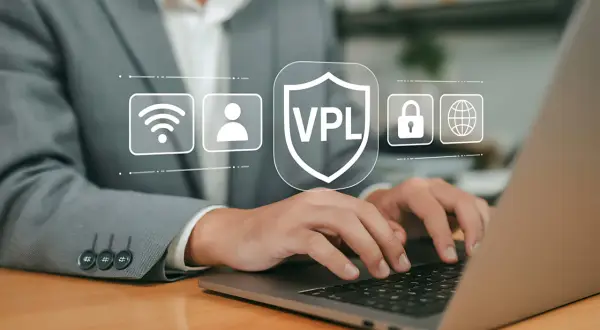 Osoba pracuje na laptopie, a nad klawiaturą wyświetlają się ikony symbolizujące bezpieczeństwo online, w tym tarcza z napisem VPL. Dowiedz się, vpn jak włączyć, by chronić swoją prywatność.