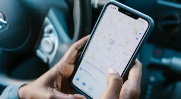 Dłonie trzymają telefon z mapą, szukając drogi. Aplikacja Zenly pomaga odnaleźć zaparkowany samochód.